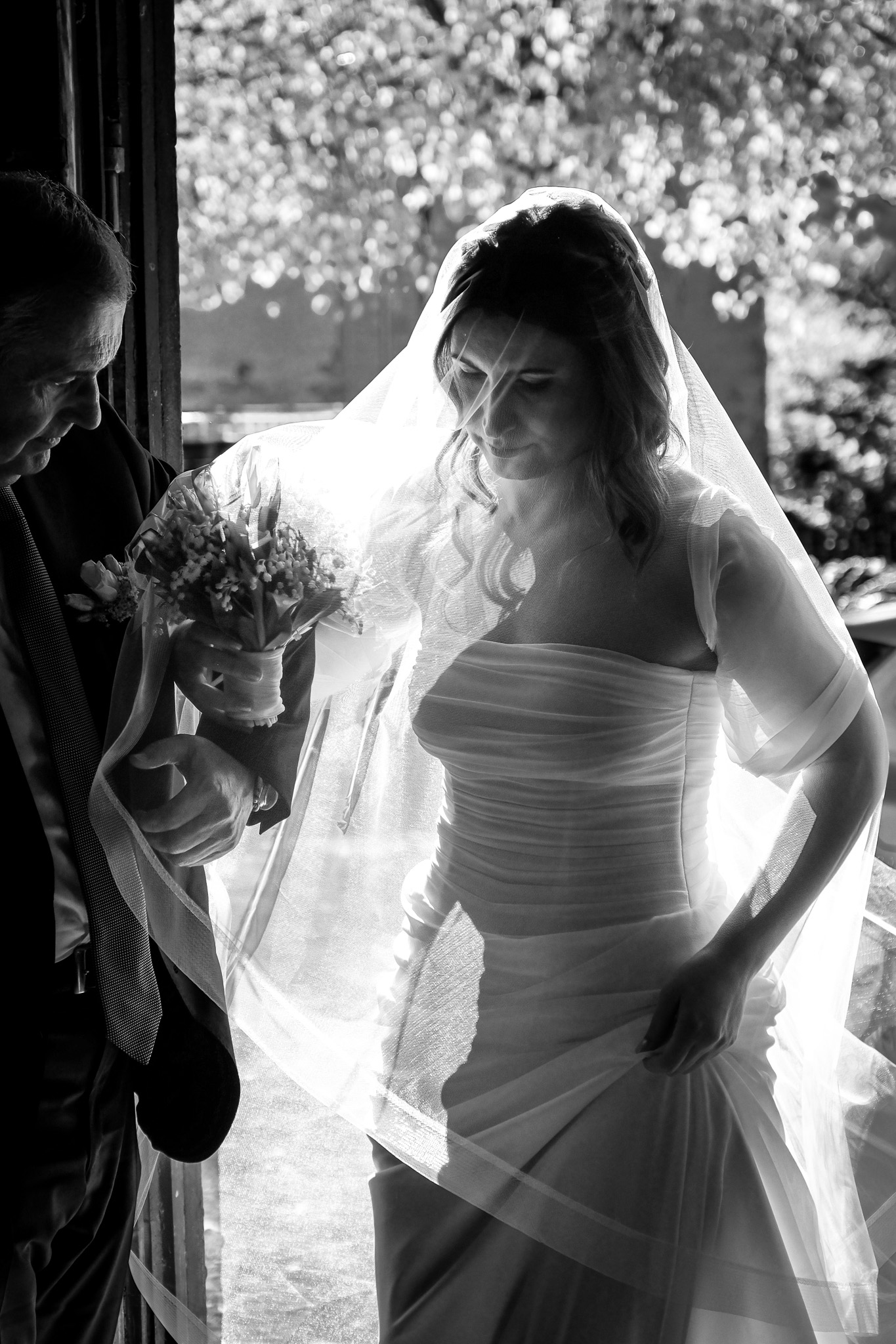 La sposa sotto il velo, controluce, al braccio del padre