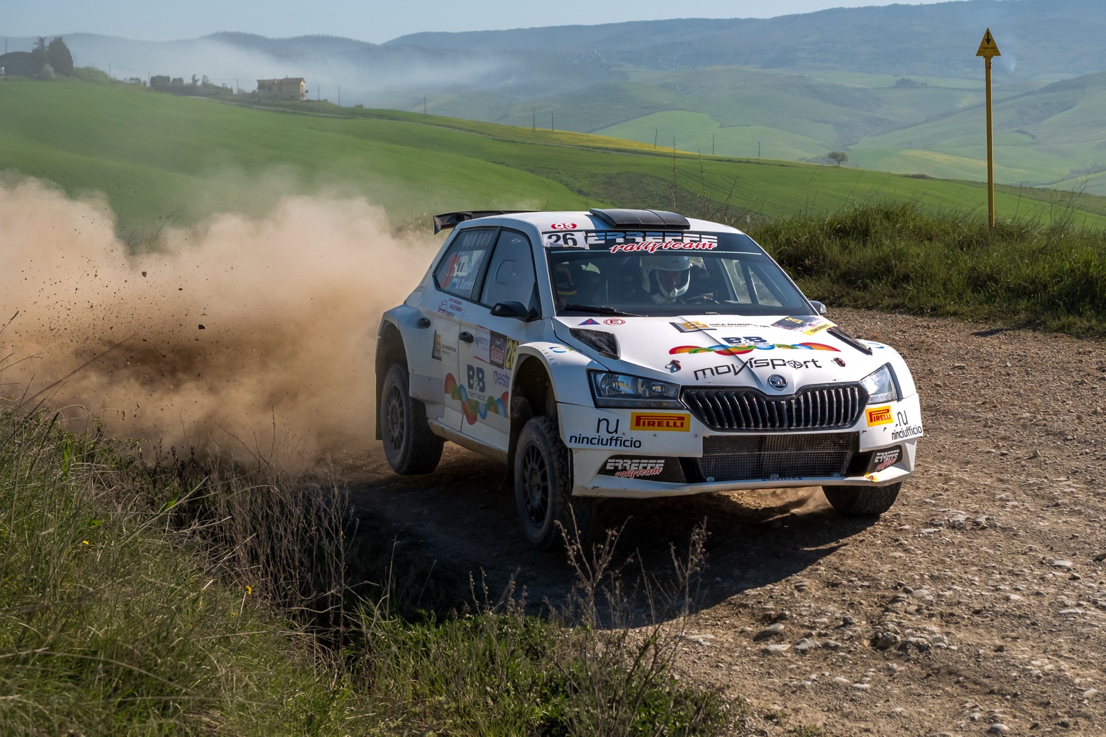Un'auto da rally di traverso in curva sullo sterrato, nella polvere
