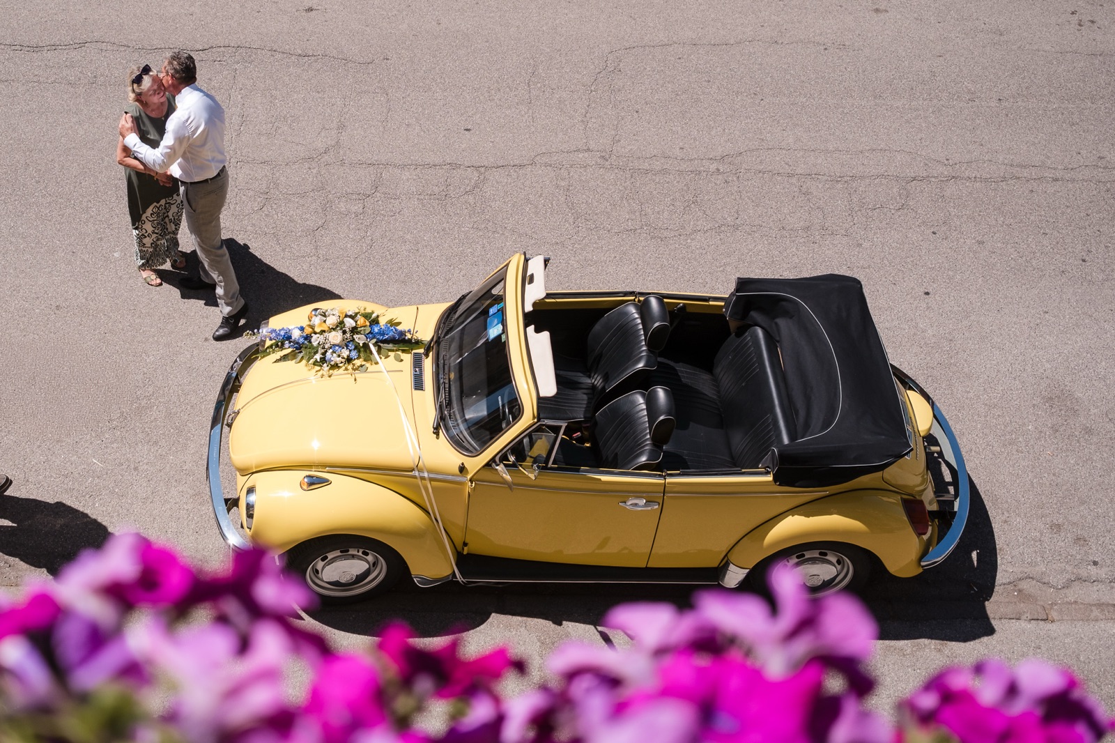 Dal balcone: il maggiolone giallo decorato di fiori e un abbraccio in strada