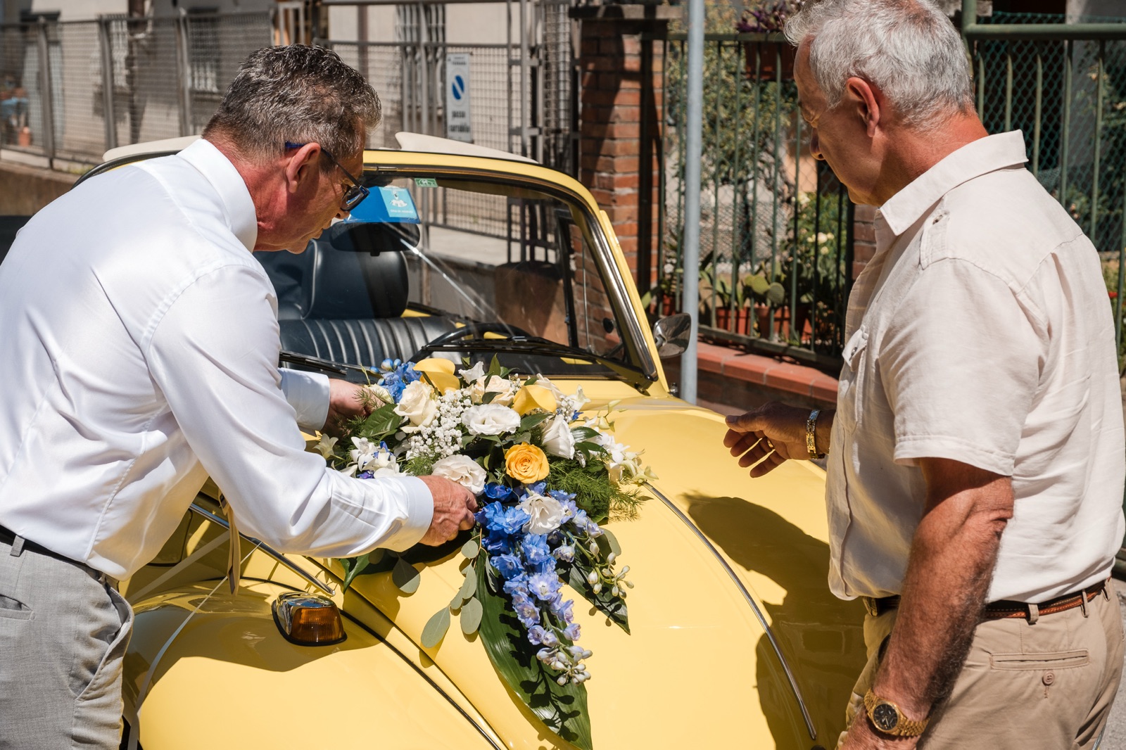 Sergio sistema i fiori sul cofano del maggiolone, un signore lo guarda