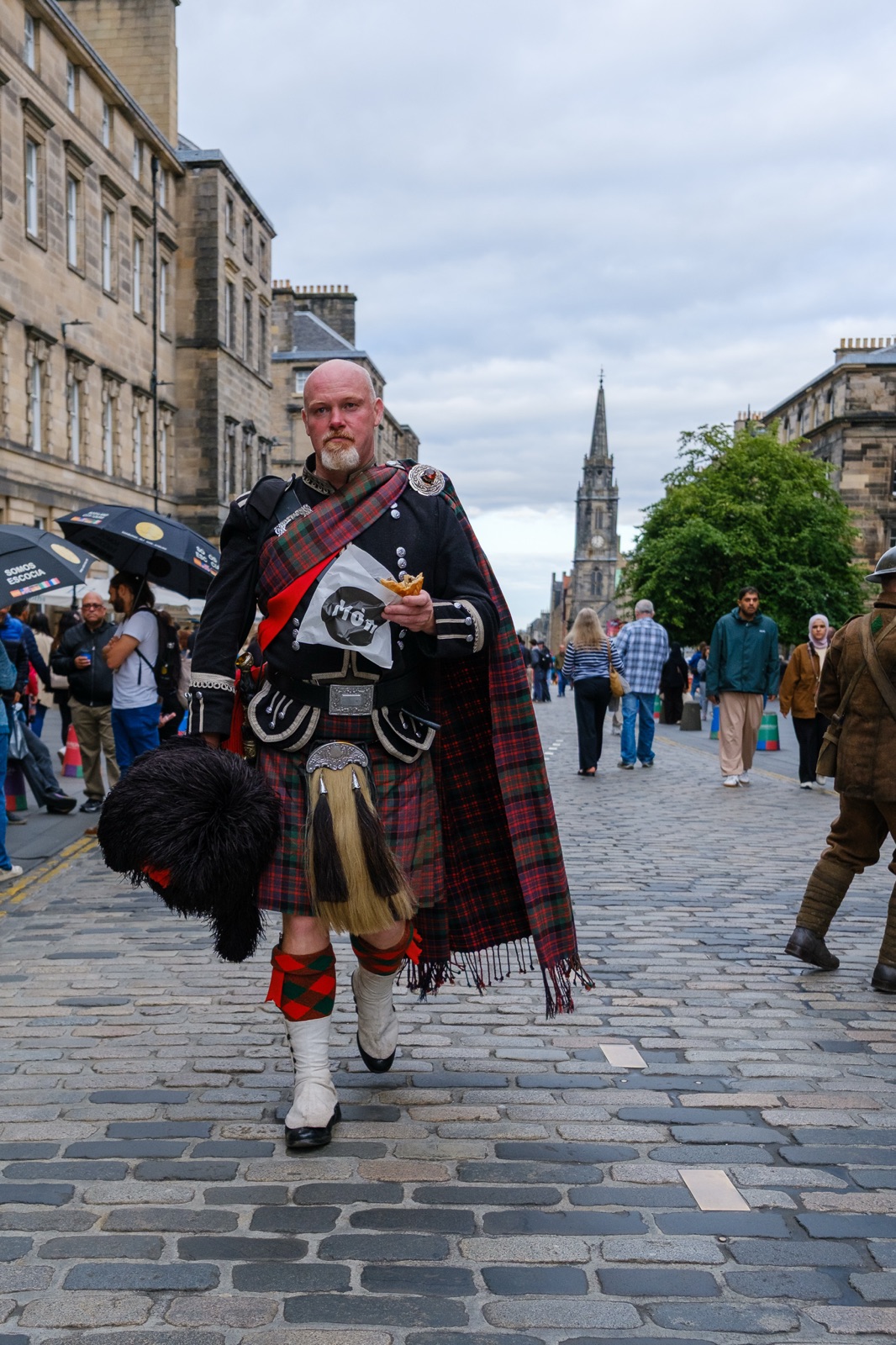 Un suonatore di cornamusa cammina sul Royal Mile tra la folla